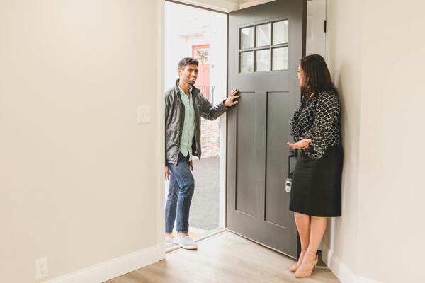 Agente dando la bienvenida al cliente dentro de la casa